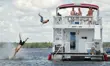 People jumping off a houseboat having fun