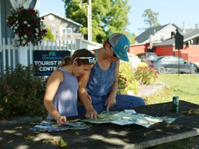 Mother and Daughter look at paddling route maps together outside the Fenelon Falls Chamber of Commerce building