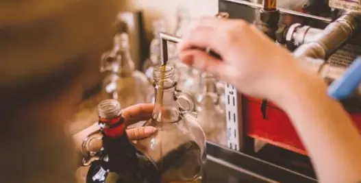 Person pouring maple syrup into a jar