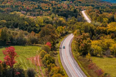 Aerial view of a road winding through the fall trees
