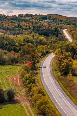Aerial view of a road winding through the fall trees